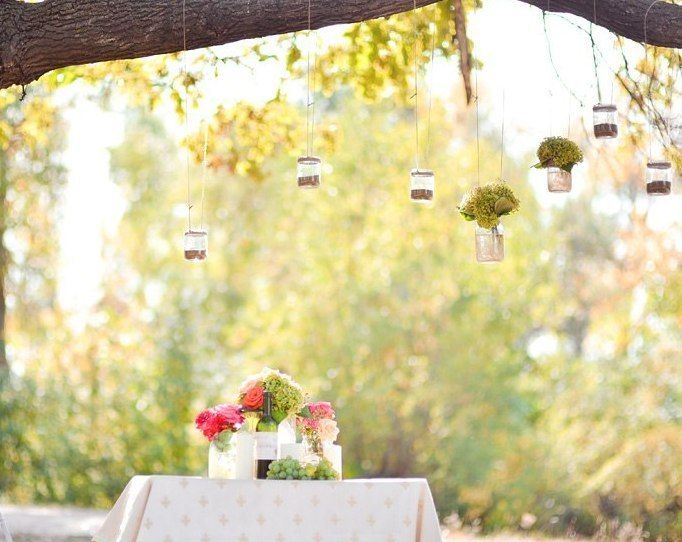 Под деревом, украшенным баночками с зеленью, стоит маленький столик с вазами розовых цветов - фото 1306487 vbkate