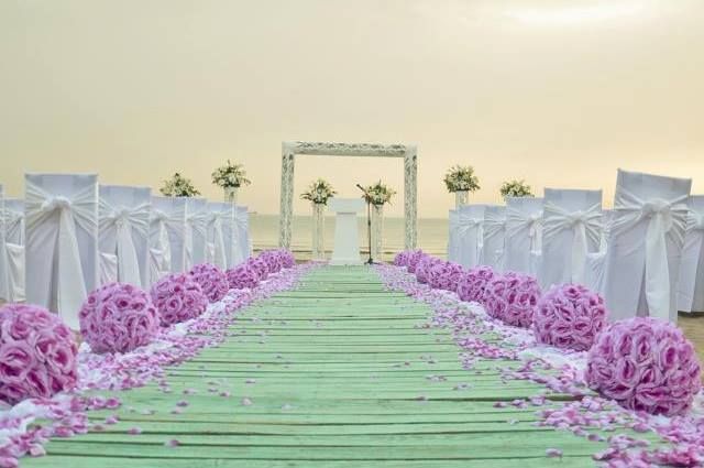 Квадратная арка с композицией из живых цветов, на фоне белых стульев для гостей с розовыми помпонами по длине прохода - фото 1108317 Свадебное агентство Wedding in Santorini