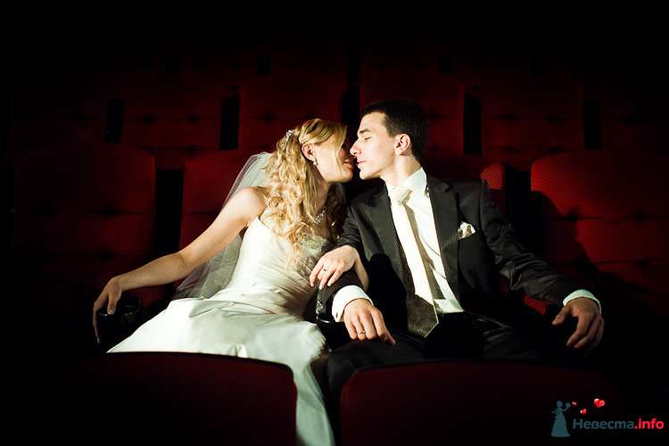 Жених и невеста сидят рядом на красных стульях в зале - фото 90920 LevBodrov