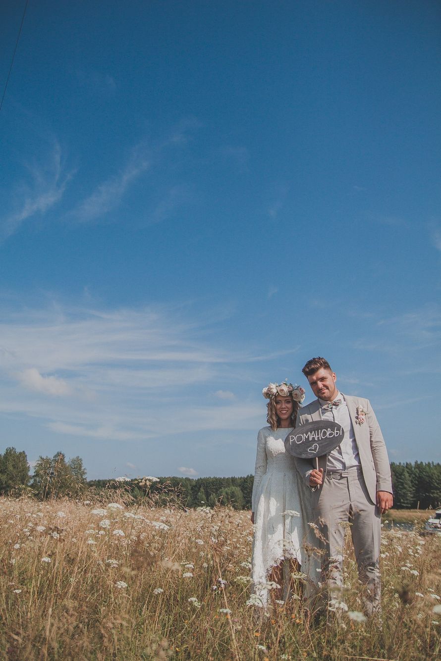 Жених и невеста, прислонившись друг к другу, стоят на фоне поля с табличкой в руках - фото 3185749 Свадебное агентство "Fashion свадьба"