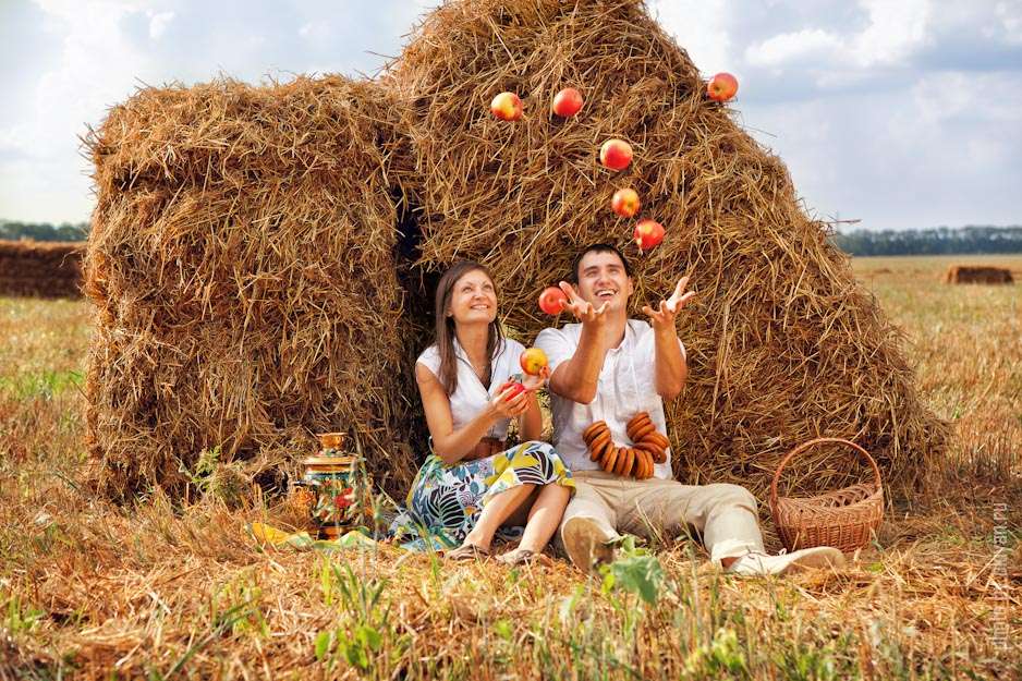Жених и невеста сидят возле стогов сена и подбрасывают спелые красные яблоки - фото 1041257 Ольга Бутко - фотограф