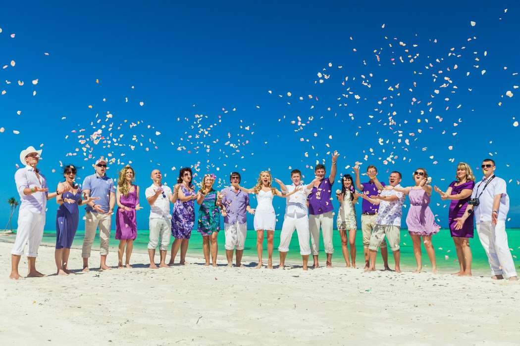 На пляже, стоят гости,хлопая и поднимая руки вверх, в сиреневых рубашках и платьях - фото 1590525 Всероссийский свадебный туроператор