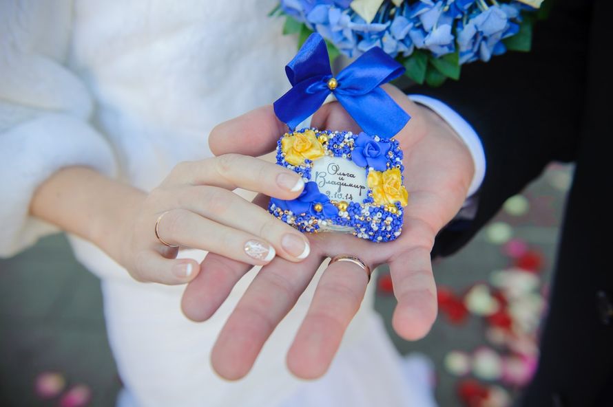 Жених и невеста держат в ладонях маленький замочек голубого цвета с желтыми цветами украшенный голубым бантом - фото 3144355 Свадебные aксессуары Лады Зайцевой