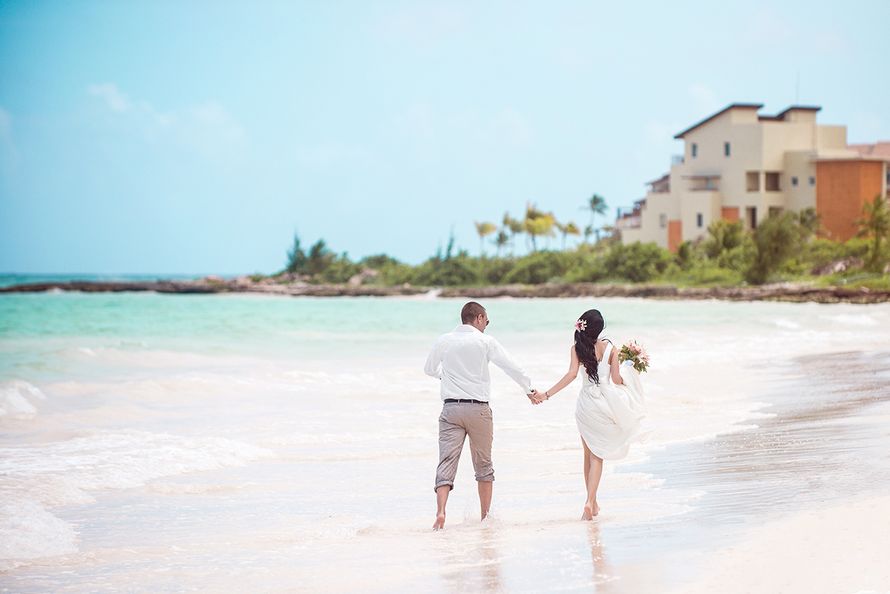 В лазурном прибое бегут молодожены, парень одет в белую рубашку и бежевые брюки, невеста - в белоснежное длинное платье, которое - фото 2939489 Свадебное агенство "Travelservice weddings"