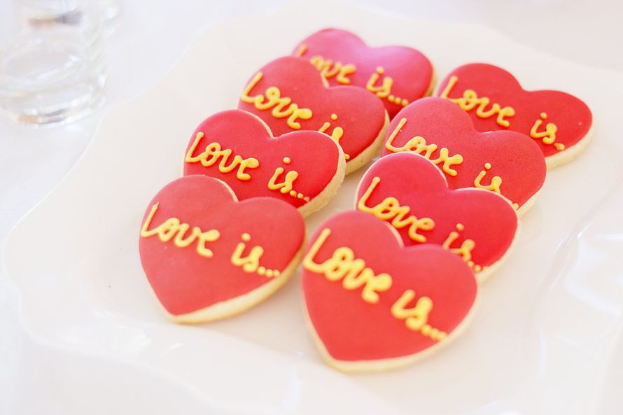 Пирожные в форме сердца, украшенные красной глазурью и надписью "Love is..." - фото 3331179 WOWdecor- студия событий - оформление 