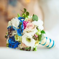 Букет невесты из белых эустом, ярко-голубых гортензий, серой брунии, нежно-розовых роз и зелени эвкалипта, ножка букета украшена голубой и белой лентами