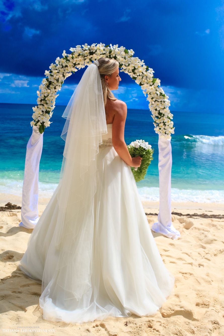 Перед свадебной аркой, украшенной белой тканью и цветами, стоит невеста в открытом белом платье с букетом белых цветов, ее волосы - фото 2643877 Свадебный фотограф Татьяна Журавлевская