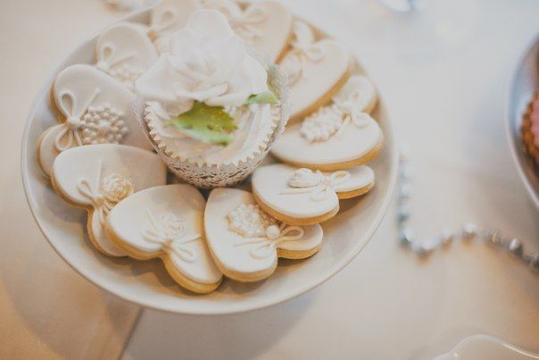 Пирожные в форме сердца, украшенные белой глазурью, декорированы бантами, на белом блюде, украшенном розой - фото 3236139 Агенство "Элегантная свадьба"