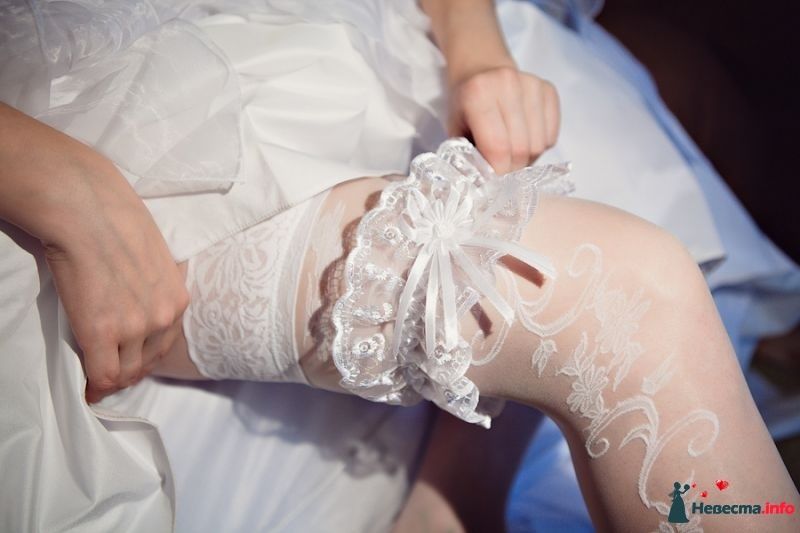 Невеста одевает на ногу белую кружевную подвязку  с атласными лентами - фото 379161 Crazy Nevesta
