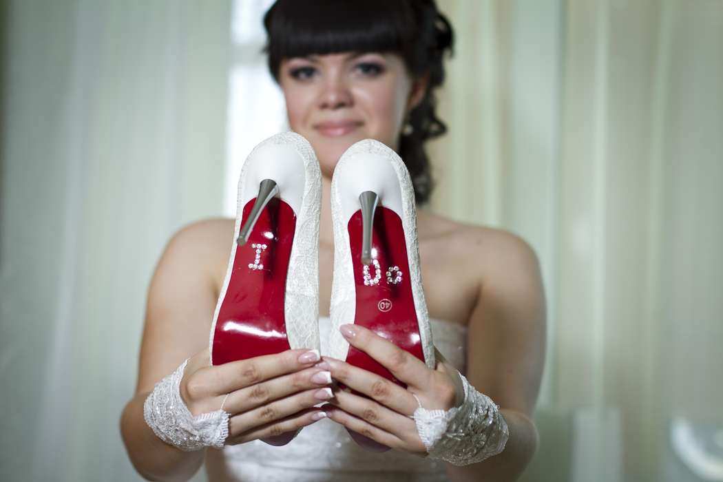 Невеста держит в руках белые туфли на железном каблуке, красной подошвой на которой камнями выложены инициалы. - фото 584946 ___Лилия____