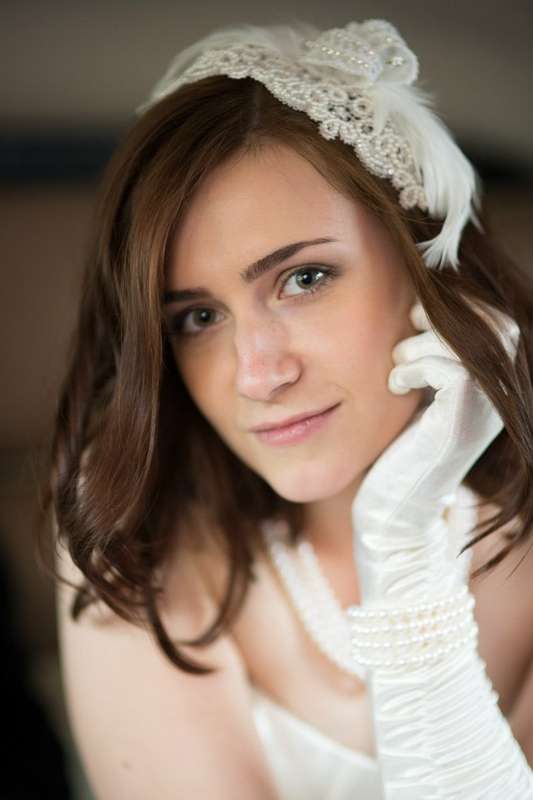 Причёску невесты украсила белая кружевная шляпка-вуалетка с жемчугом и перьями, а на руках высокие атласные перчатки и жемчужный - фото 1191351 Александра Cherry - стилист