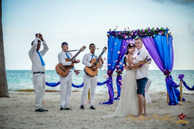 На песчаном пляже на фоне свадебного шатра, украшенного синей и сиреневой тканью, танцуют молодожены, жених в черных бриджах и - фото 2848145 Caribbean Wedding - свадьба в Доминикане