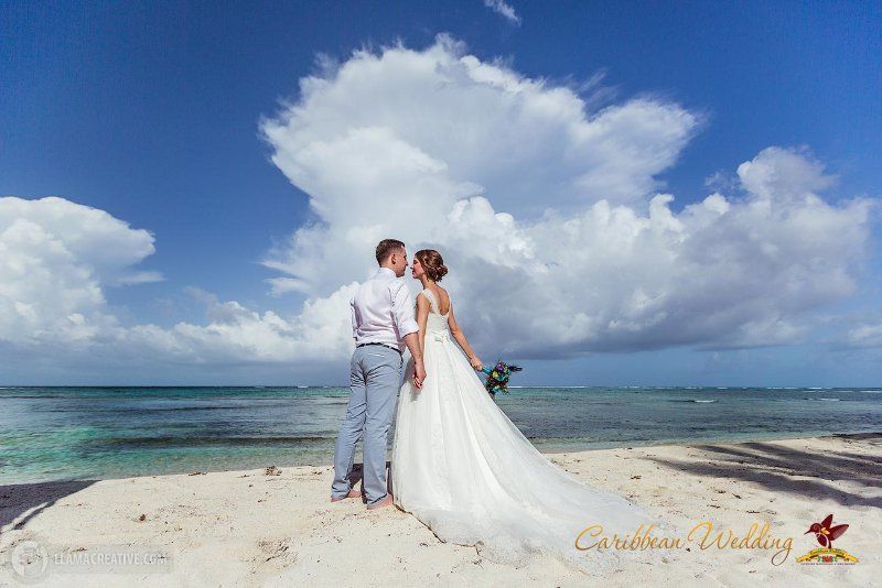 На фоне моря , держась за руки, стоят молодожены, невеста в белом платье с букетом в руках, жених в белой рубашке с бабочкой и - фото 3212153 Caribbean Wedding - свадьба в Доминикане