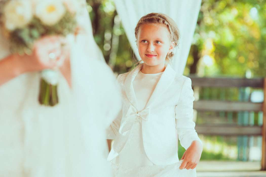 Девочка в белом красивом платье с болеро, стоит нежно смотря на невесту и держит руками платье - фото 1613578 Фотографы Даша Жукова и Владимир Шаповалов